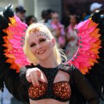 Girl pointing at camera with pink and black feathered wings