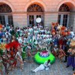 Samba group with dancers and flag bearers, dancers are dressed in full samba costume and bateria members are wearing their white and green uniforms