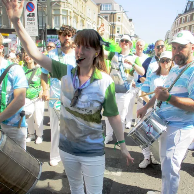 Stacey leading the bateria. Group of people playing Samba instruments following the director