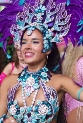 Smiling samba girl with feathered head wear, she wears purple feathed headdress with blue jewels - Copyright Paul Lipiatt