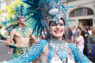 Beautiful samba dancer close up, the girl smiles at the camera with a blue feathered head dress adorned with jewels