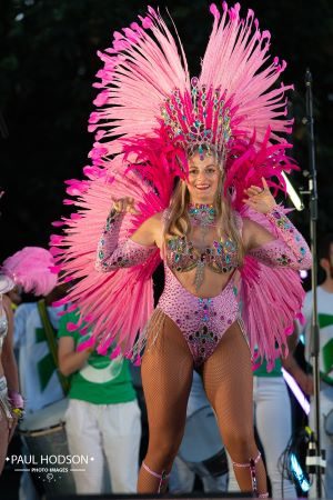 London School of Samba Dancer smiling on stage in full samba dance costume with pink feathers at Panorama 2021